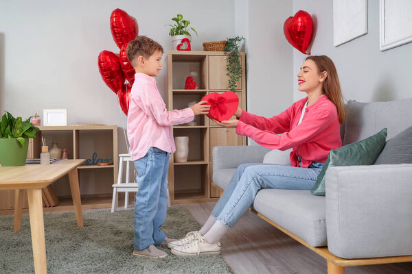 Маленький мальчик поздравляет свою мать с подарком дома на День Святого Валентина