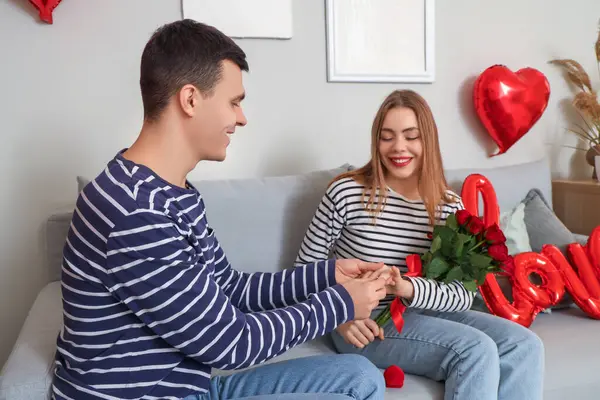 Genç adam Sevgililer Günü 'nde evde karısının parmağına nişan yüzüğü takıyor.