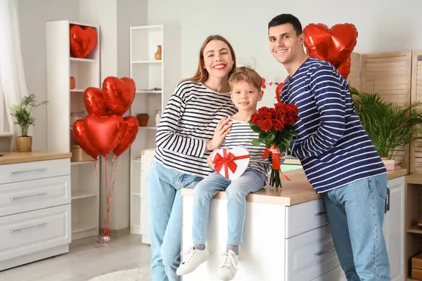 Little boy with gifts and his parents in kitchen on Valentine\'s Day
