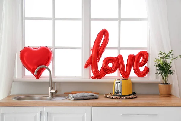 Word LOVE made of balloons on windowsill in kitchen. Valentine\'s Day celebration