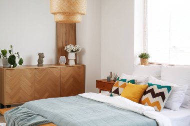 Yatak odasının içi ahşap dolap ve pencerenin yanında rahat yatak.