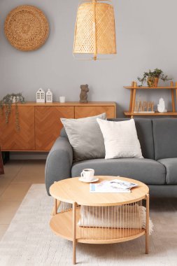 Gri kanepesi, ahşap dolabı ve sehpası olan oturma odasının içinde.