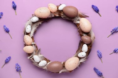 Mor arka planda yumurta ve tüylü Paskalya çelengi