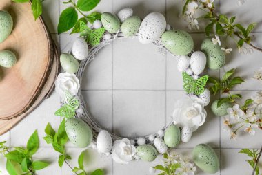 Paskalya çelengi, çiçeklerden, yumurtalardan ve beyaz fayanslı dalları olan kelebeklerden yapılmıştır.