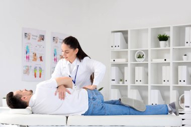 Rehabilitasyon merkezinde genç bir adamla çalışan kadın fizyoterapist.
