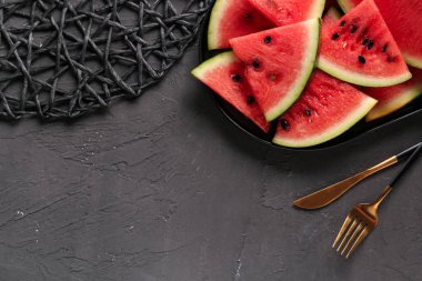 Siyah zemin üzerinde taze karpuz parçaları olan bir tabak.