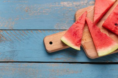Mavi ahşap arka planda taze karpuz parçaları olan tahta.