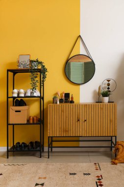 Ayna, ahşap dolap ve ayakkabı standı olan şık bir koridor.