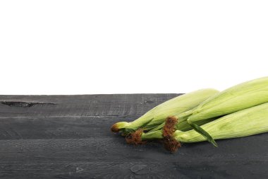 Beyaz arka planda siyah ahşap masada taze mısır koçanları