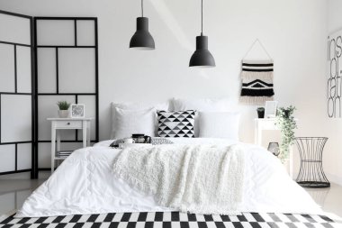 Beyaz battaniyeli rahat yatak ve şık yatak odasının içinde yastıklar.