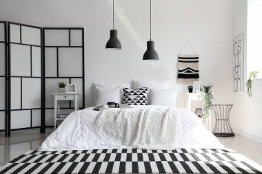 Beyaz battaniyeli rahat yatak ve şık yatak odasının içinde yastıklar.