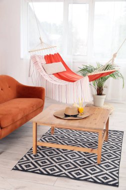 Hamağı, kahverengi kanepesi ve kahve masası olan şık bir oturma odası.