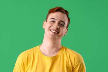 Yeşil arka planda gülümseyen genç adam, yakın plan