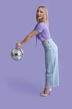 Mor arka planda disko topu olan güzel genç bir kadın.