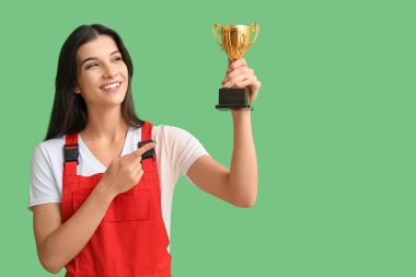 Yeşil arka planda altın bardağa bakan kadın işçi