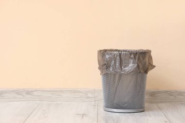 Bej duvarın yanında çöp torbası olan boş çöp kutusu