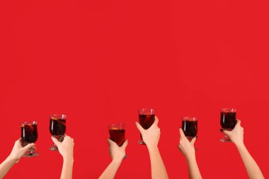 Kırmızı arka planda sıcak şarap kadehleriyle kadın elleri.