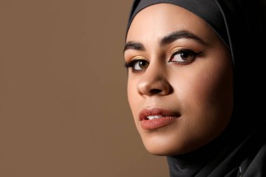 Kahverengi arka planda güzel makyajlı güzel bir Afro-Amerikalı Müslüman kadın.
