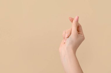 Kadın eli bej arka planda kalp hareketi gösteriyor. Sevgililer Günü kutlaması