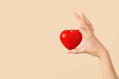 Bej arka planda kalbi olan bir kadın. Sevgililer Günü kutlaması