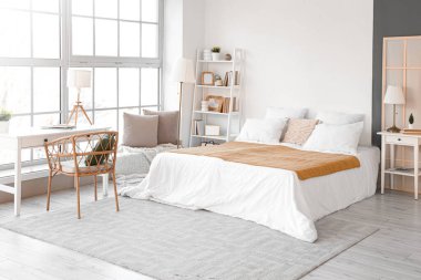 Masaları ve raf ünitesi olan aydınlık yatak odasının içi.