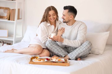 Sevgililer Günü 'nde yatakta kahvaltı yapan genç çift.