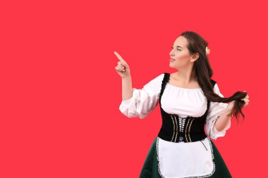 Geleneksel kostümlü genç kadın kırmızı arka plandaki bir şeyi işaret ediyor. Aziz Patrick Günü kutlaması