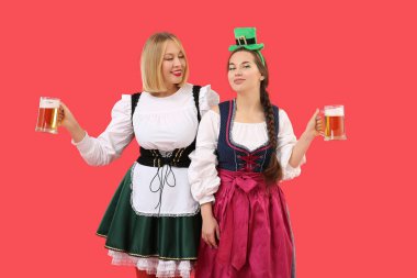 Kırmızı arka planda Aziz Patrick Günü 'nü kutlayan biralı mutlu kadınlar