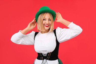 Kırmızı arka planda yeşil şapkalı mutlu kadın. Aziz Patrick Günü kutlaması