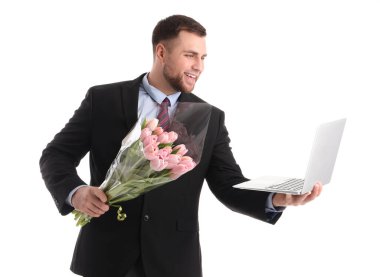Beyaz arka planda laleleri ve dizüstü bilgisayarı olan yakışıklı bir iş adamı. Uluslararası Kadınlar Günü kutlamaları