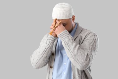 Hafif arkaplanda tespih taşıyan genç Müslüman bir adam. Ramazan kutlaması