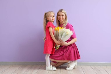 Laleli küçük bir kız ve annesi leylak duvarın yanında. Uluslararası Kadınlar Günü kutlamaları