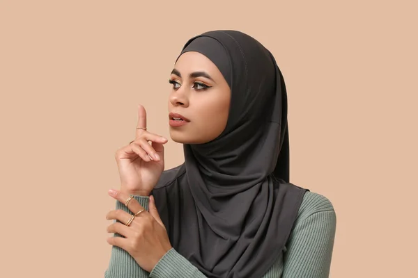 Pretty young African-American Muslim woman with beautiful makeup on beige background