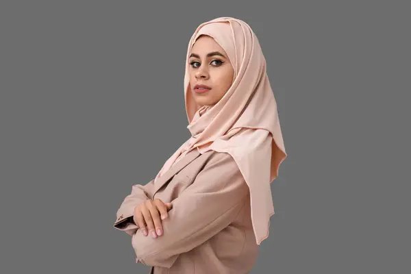 Stylish young African-American Muslim woman with beautiful makeup on grey background