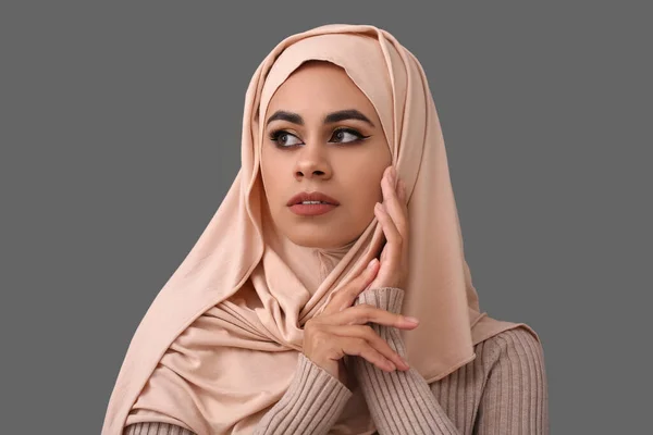 Pretty young African-American Muslim woman with beautiful makeup on grey background