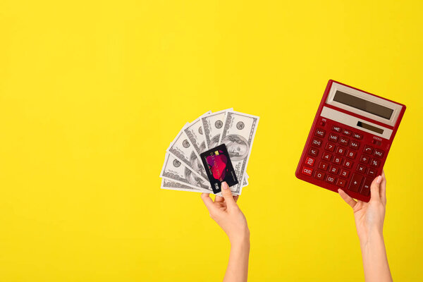 Woman with credit card, calculator and dollar banknotes on yellow background