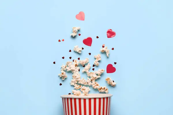 Bucket of popcorn with hearts decor on blue background. Valentine\'s Day celebration