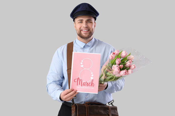 Handsome postman with tulips and greeting card on light background. International Women's Day celebration