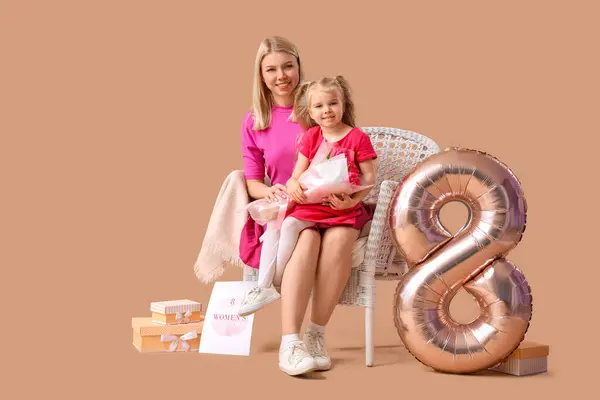 带着郁金香的小女孩和她的母亲坐在米色背景的扶手椅上 国际妇女节庆祝活动 — 图库照片