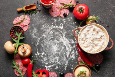 Koyu arkaplanda pizza hazırlamak için farklı malzemeler.