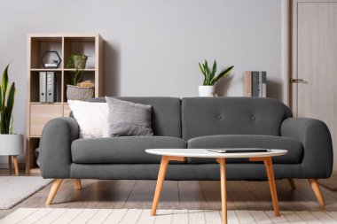 Masada dizüstü bilgisayarı ve kanepesi olan modern oturma odasının içinde.