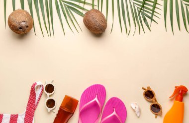 Palmiye yaprakları, hindistan cevizleri ve bej arka planda farklı plaj aksesuarları olan kompozisyon