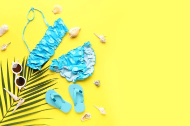 Plaj aksesuarları ve sarı arka planda palmiye yaprağı olan kompozisyon