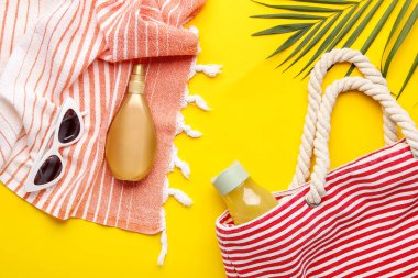 Plaj aksesuarları ve sarı arka planda palmiye yaprağı olan kompozisyon