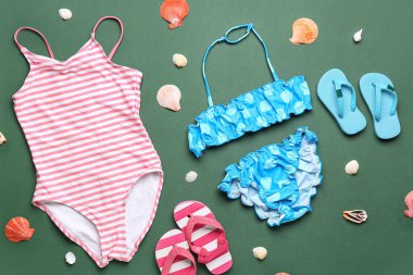 Çocuklar için plaj aksesuarları ve yeşil arka planda deniz kabukları olan kompozisyon