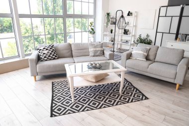 Gri kanepeleri ve kahve masası olan aydınlık oturma odasının içinde.