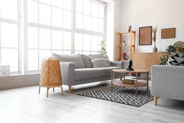 Işıl ışıl oturma odasının içi rahat gri kanepe ve ahşap sehpa.