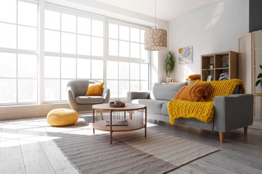 Gri kanepesi, koltuğu ve ahşap sehpası olan aydınlık oturma odasının içinde.