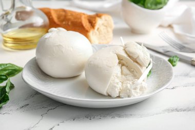 Beyaz arka planda fesleğenli ve baget soslu lezzetli Burrata peyniri tabağı.
