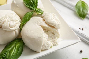 Beyaz arka planda fesleğenli lezzetli Burrata peyniri tabağı